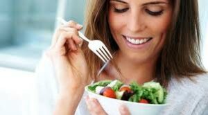 Chica comiendo ensalada para obtener vitaminas y minerales para la piel